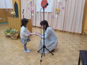 担任から帳面をもらっている女の子