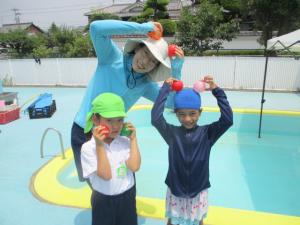 プールで先生と子ども達とボールを持って写真を撮っている
