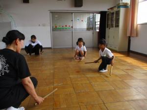 リズム室の床を太鼓のバチで叩いている子ども