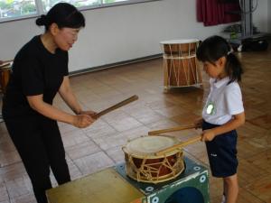 太鼓の叩き方を教えてもらう子ども