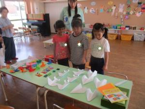 机の上にある折り紙を見つめる子ども達