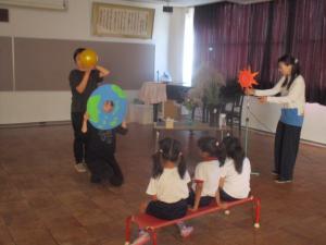 太陽と月と地球についての話を聞いている子ども