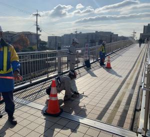 昼間、歩道橋の点検作業をしている画像