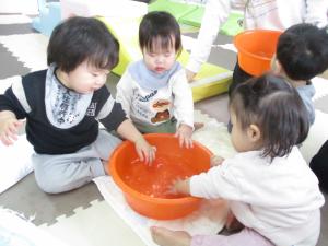 たらいに入ったお湯を触る子供たち