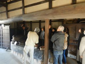 旧細田家の土間でかまどや建物の説明を聞く様子