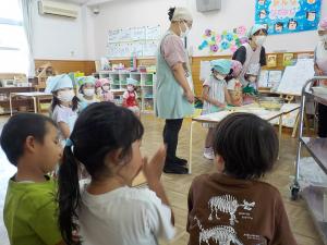 調理する年長児たちを見ている3歳児