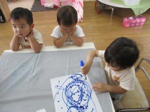 1人が絵を描く様子を2人が見ている