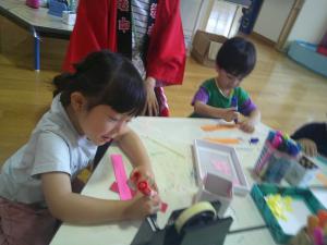 紙飛行機づくりをする３歳児