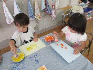 2人の子どもがタンポを持って絵を描いています。