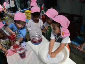 4人の子どもが色水を使って遊んでいます。