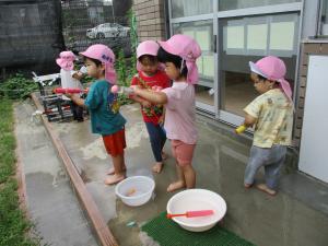 ４人の子どもが水鉄砲を使って遊んでいます。