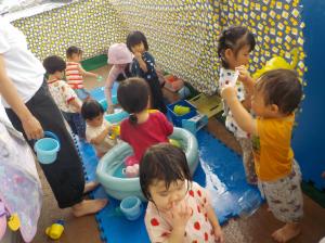 小さいプールで水遊びする子ども