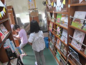 移動図書のバスの中で本を選ぶ子供