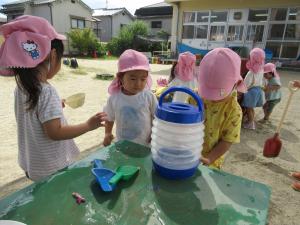 ３人でタンクから水を汲んでいる