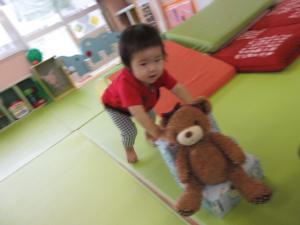 クマのぬいぐるみを椅子に乗せて押して遊んでいる